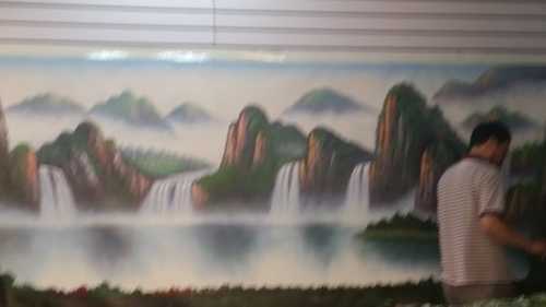 Blurry photo but a painter is painting this huge montage painter
